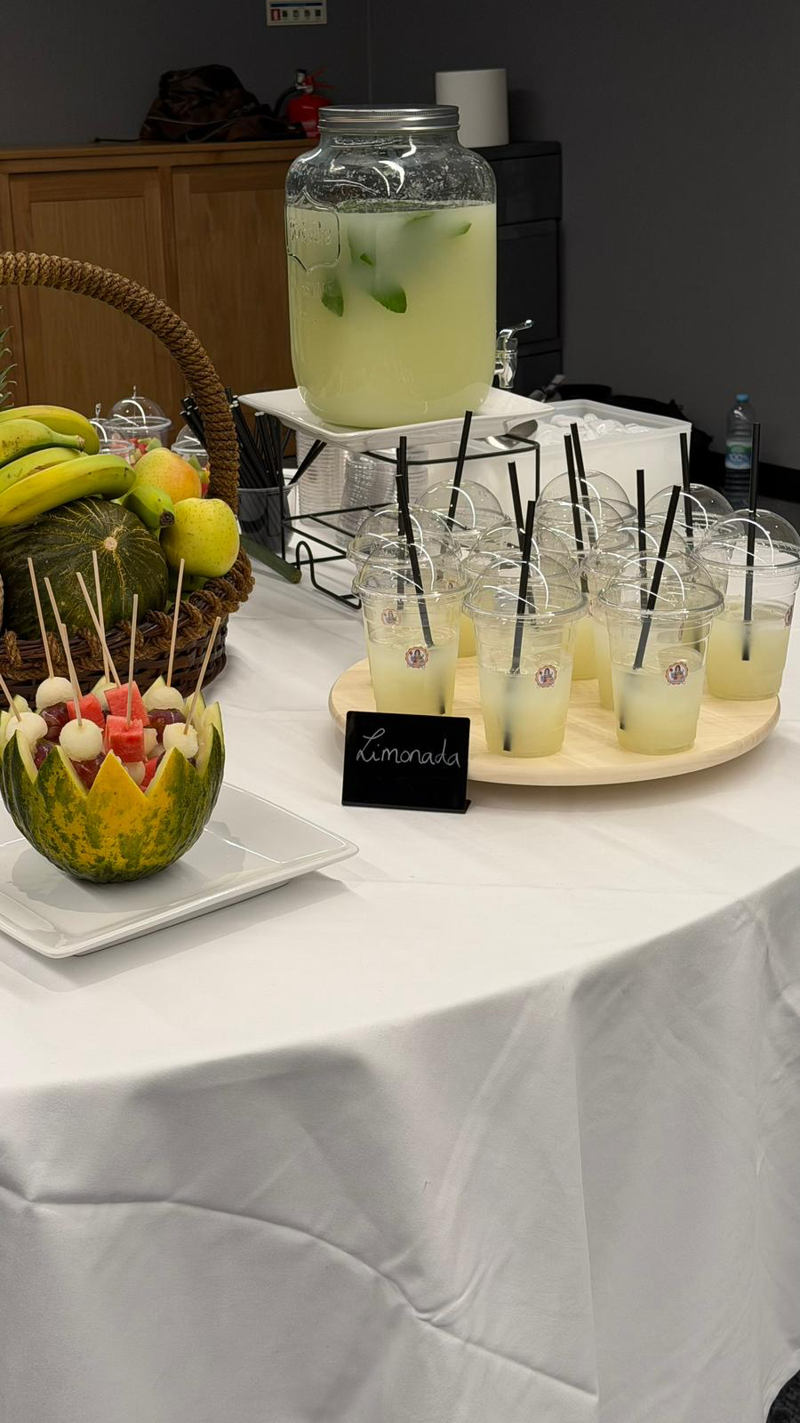 Mesa de catering July com limonada natural e cesto de fruta